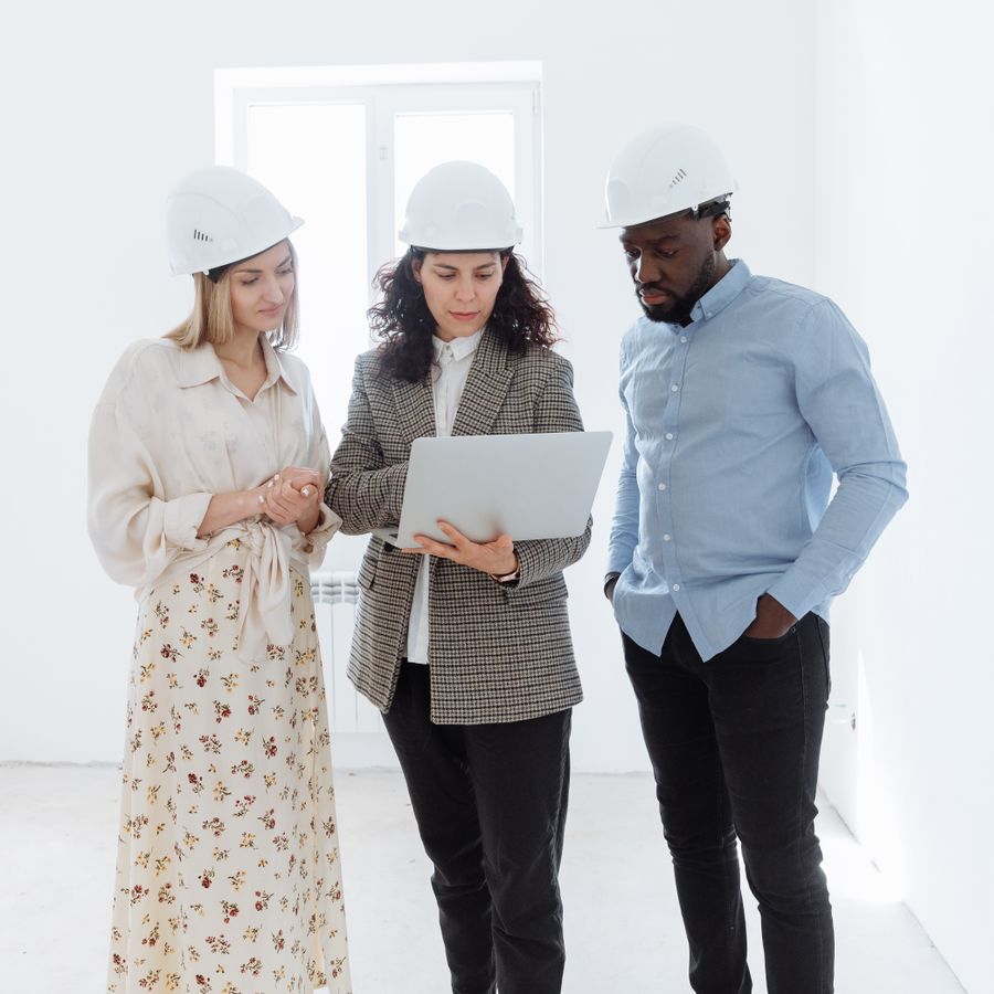 Construction professionals wearing hard hats reviewing a laptop